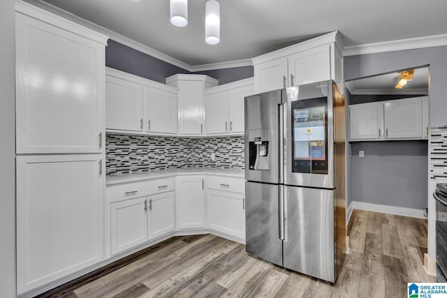 kitchen featuring tasteful backsplash, stainless steel fridge, and white cabinets