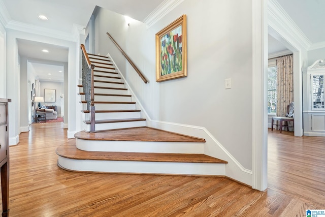 staircase with crown molding and wood-type flooring