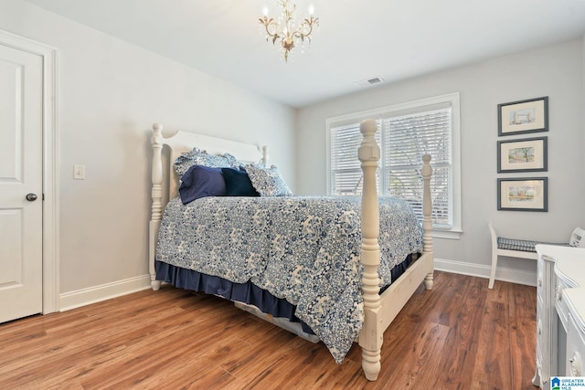 bedroom with hardwood / wood-style floors and a notable chandelier