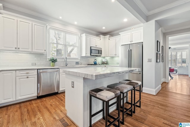 kitchen featuring stainless steel appliances, white cabinetry, a kitchen island, and sink