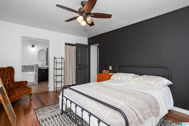 bedroom featuring connected bathroom, sink, a textured ceiling, dark hardwood / wood-style flooring, and ceiling fan