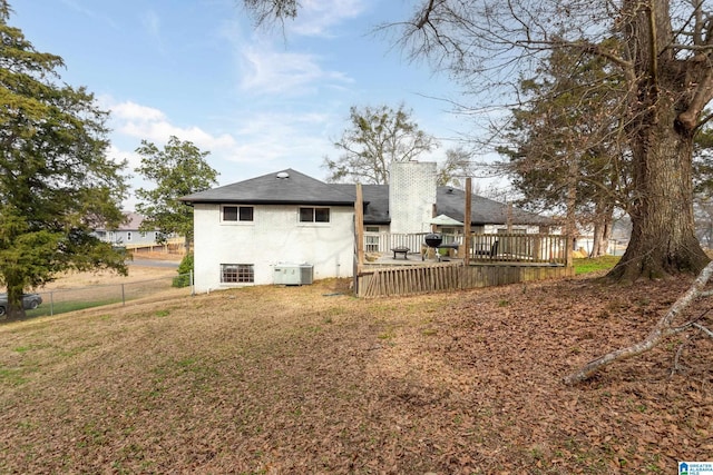 rear view of house with a wooden deck, a yard, and central AC