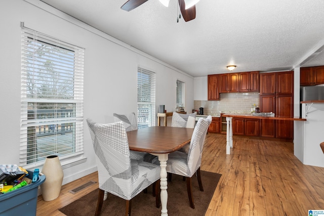 dining area with ceiling fan, a textured ceiling, and light hardwood / wood-style floors