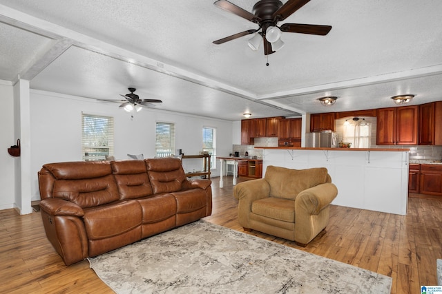 living room featuring ceiling fan, a textured ceiling, and light wood-type flooring