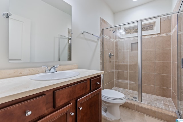 bathroom featuring walk in shower, vanity, toilet, and tile patterned flooring