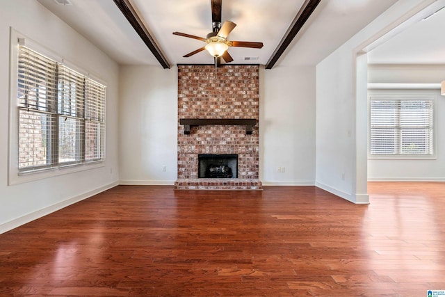 unfurnished living room featuring beamed ceiling, a brick fireplace, and a wealth of natural light