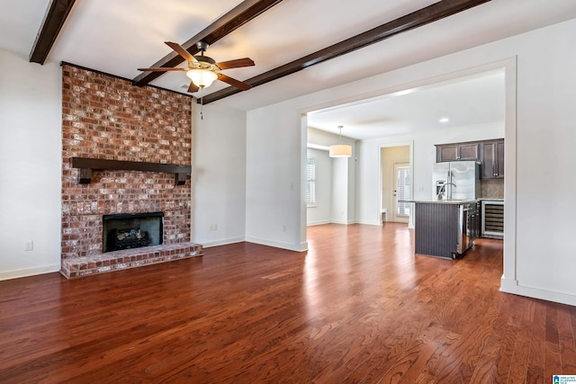 unfurnished living room with beamed ceiling, beverage cooler, dark hardwood / wood-style flooring, and a fireplace