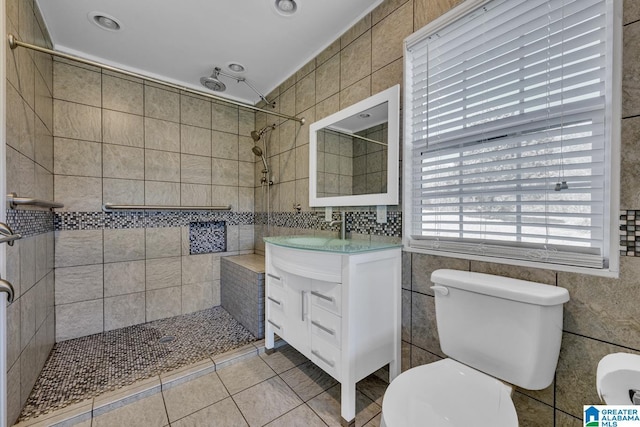 bathroom featuring tile patterned flooring, vanity, toilet, and a tile shower