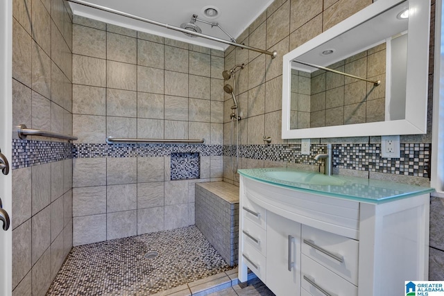 bathroom featuring tiled shower, vanity, and backsplash