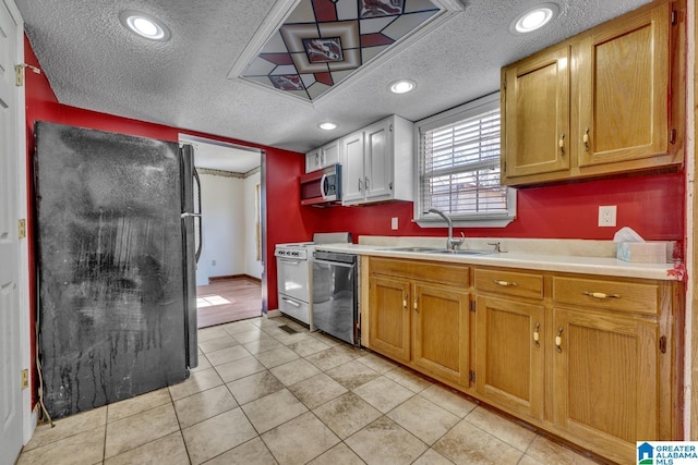 kitchen with sink, light tile patterned floors, stainless steel appliances, and a textured ceiling