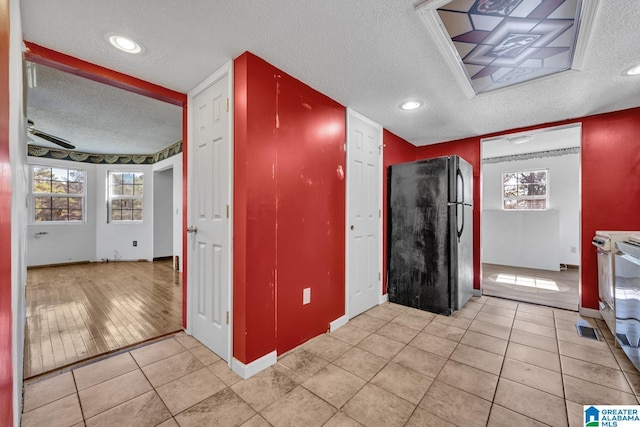 kitchen with light tile patterned floors, range, a textured ceiling, and black fridge