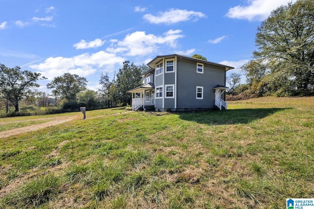 view of side of property with covered porch and a lawn