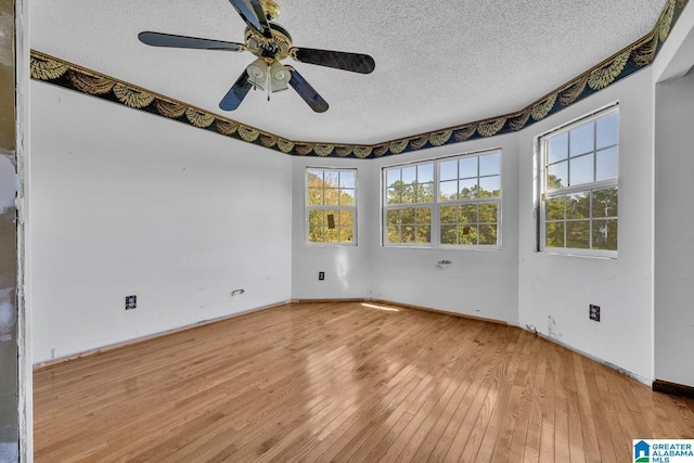 spare room featuring ceiling fan, plenty of natural light, a textured ceiling, and light hardwood / wood-style flooring