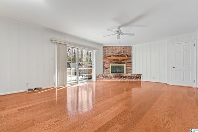 unfurnished living room with crown molding, a fireplace, light hardwood / wood-style floors, and ceiling fan