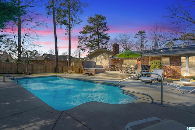 pool at dusk with a patio area