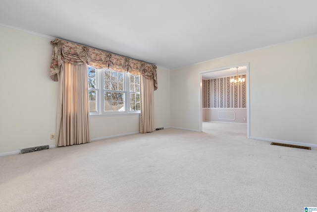 carpeted spare room featuring ornamental molding and an inviting chandelier