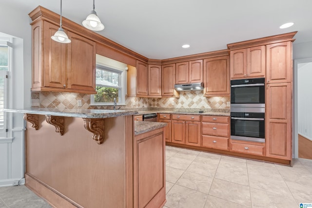 kitchen with light tile patterned flooring, appliances with stainless steel finishes, decorative light fixtures, a kitchen breakfast bar, and kitchen peninsula