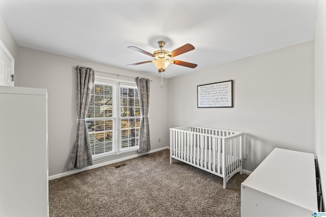 carpeted bedroom featuring a nursery area and ceiling fan