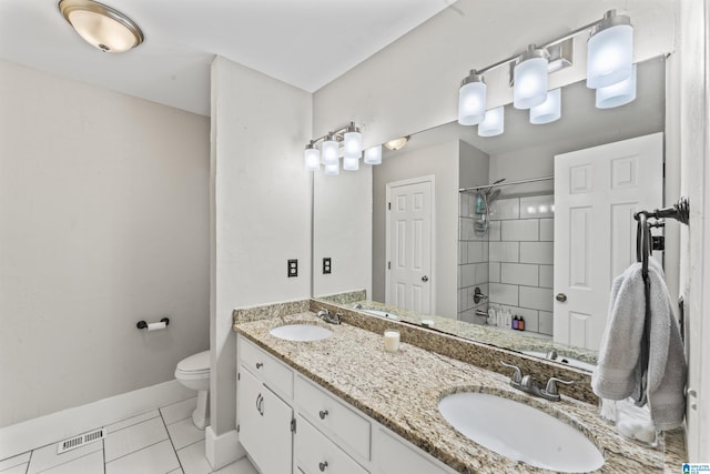 bathroom with tile patterned flooring, vanity, tiled shower, and toilet