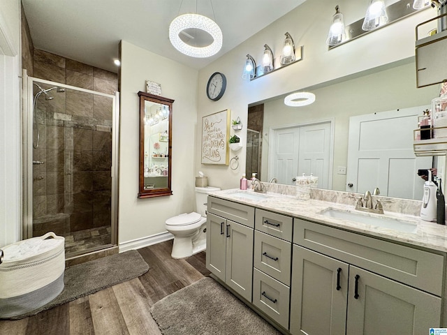 bathroom with a shower with door, vanity, hardwood / wood-style floors, and toilet