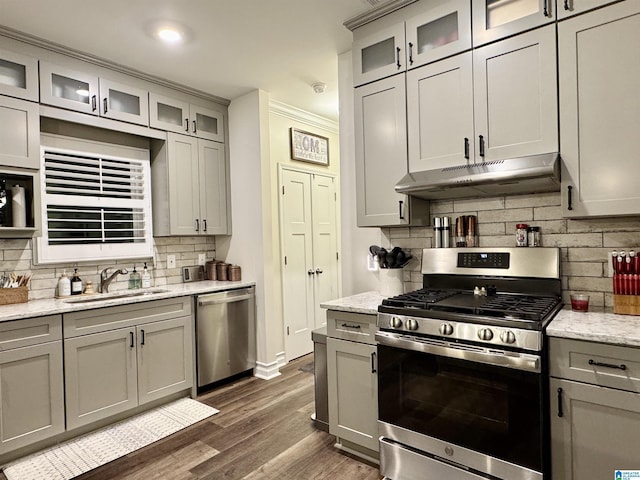 kitchen with sink, appliances with stainless steel finishes, gray cabinetry, light stone counters, and dark hardwood / wood-style flooring