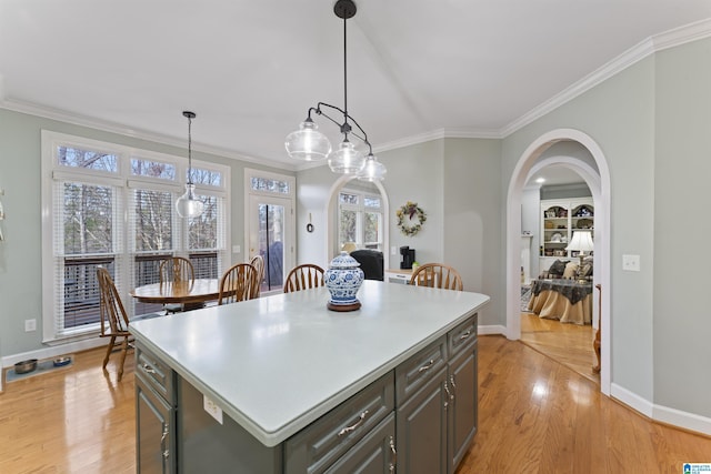 kitchen featuring crown molding, gray cabinets, a kitchen island, pendant lighting, and light hardwood / wood-style floors