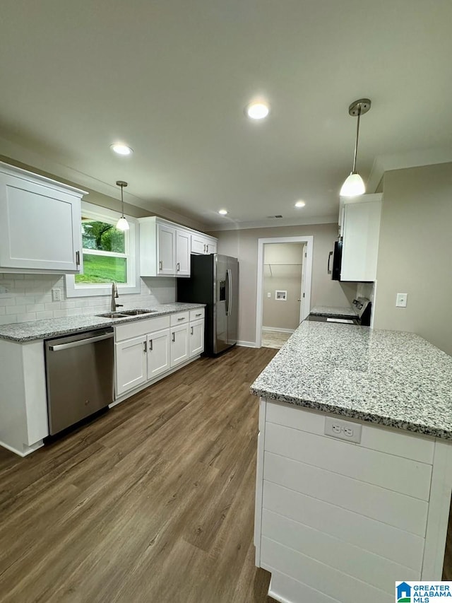 kitchen featuring hanging light fixtures, appliances with stainless steel finishes, sink, and white cabinets