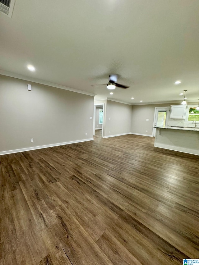 unfurnished living room featuring ceiling fan, crown molding, and dark hardwood / wood-style flooring