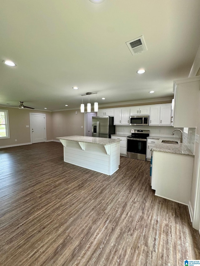 kitchen featuring pendant lighting, sink, appliances with stainless steel finishes, white cabinetry, and a center island