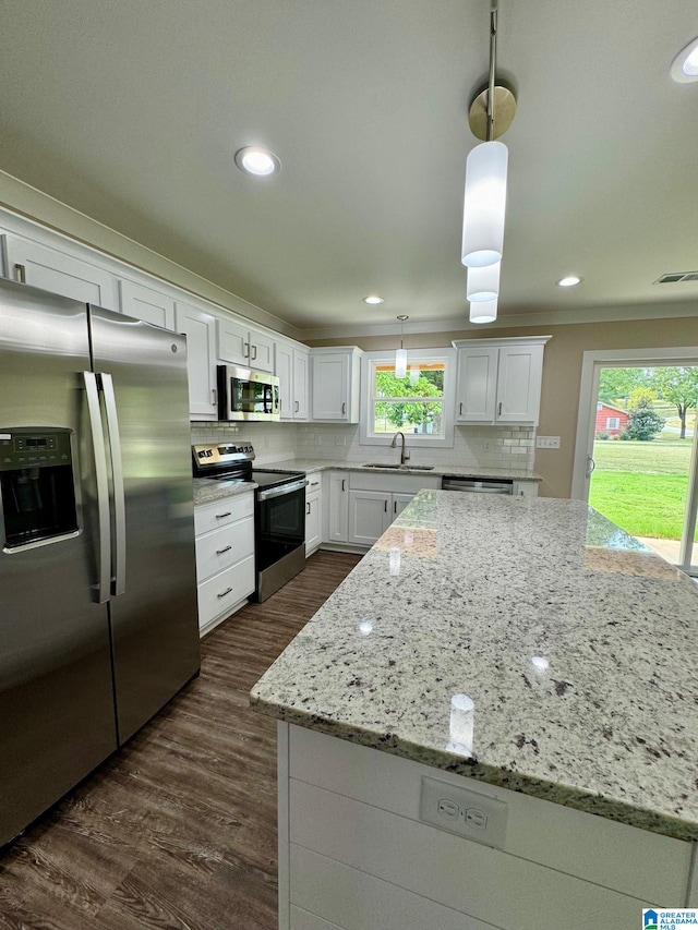 kitchen with pendant lighting, sink, appliances with stainless steel finishes, white cabinets, and decorative backsplash