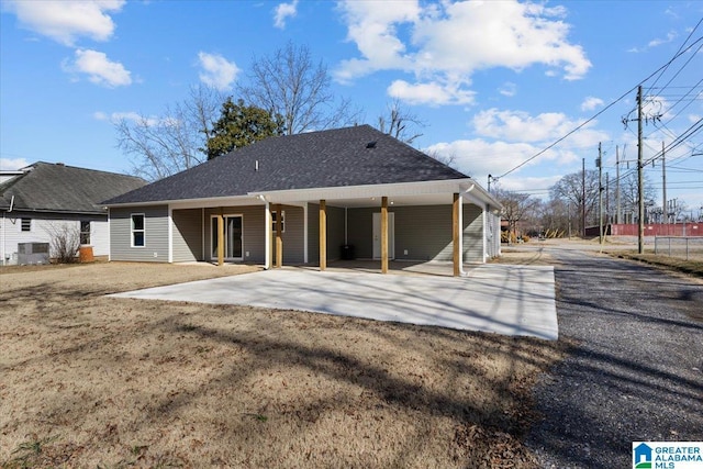 rear view of house featuring a lawn, a carport, and central air condition unit