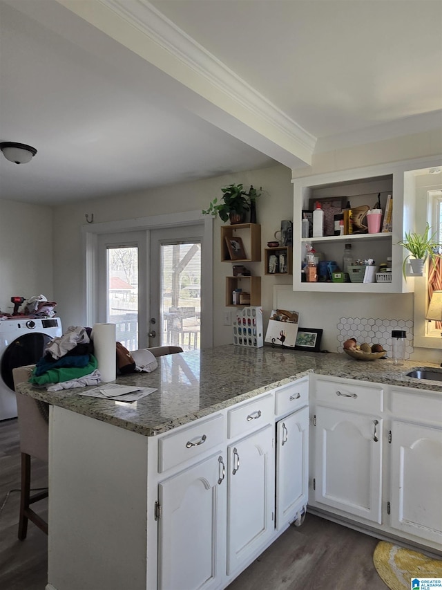 kitchen with white cabinetry, light stone counters, dark hardwood / wood-style floors, kitchen peninsula, and washer / clothes dryer