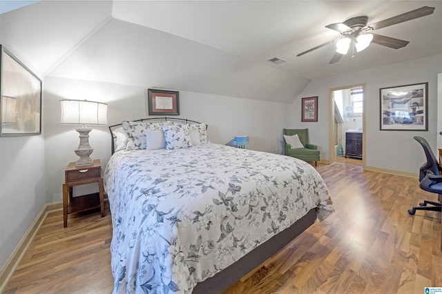 bedroom featuring lofted ceiling, ensuite bath, ceiling fan, and hardwood / wood-style flooring