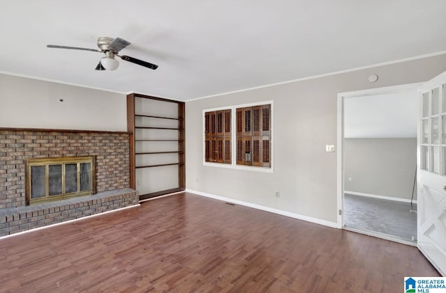 unfurnished living room with dark hardwood / wood-style flooring, a brick fireplace, crown molding, and ceiling fan