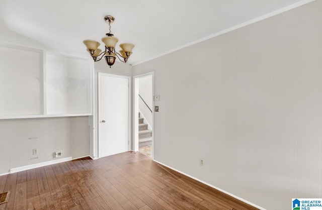 spare room featuring ornamental molding, a chandelier, and hardwood / wood-style floors