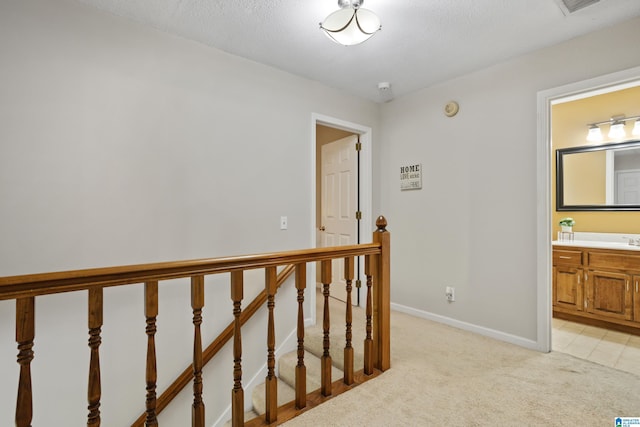 hall featuring light carpet and a textured ceiling