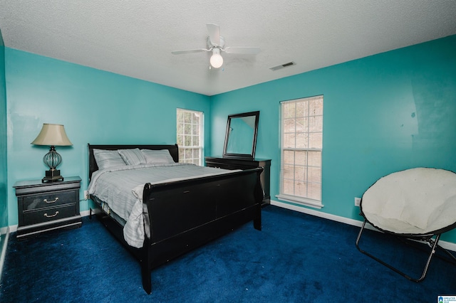 carpeted bedroom featuring ceiling fan and a textured ceiling