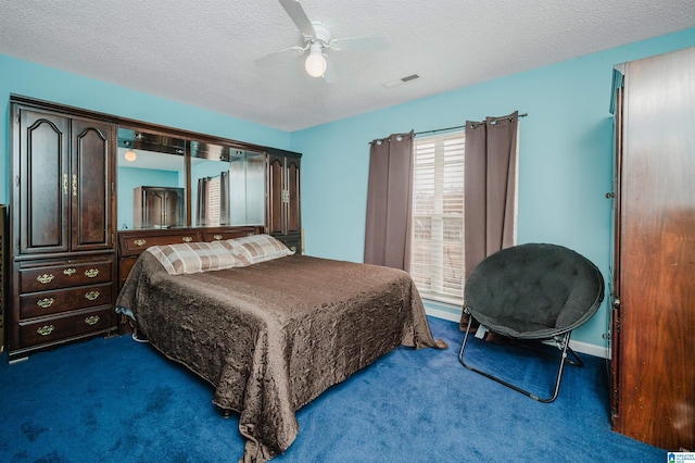 bedroom with ceiling fan, dark carpet, and a textured ceiling