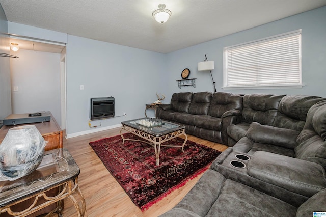 living room featuring wood-type flooring, heating unit, and a textured ceiling