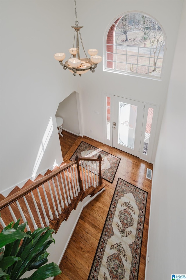 entryway with a chandelier, hardwood / wood-style floors, and a high ceiling