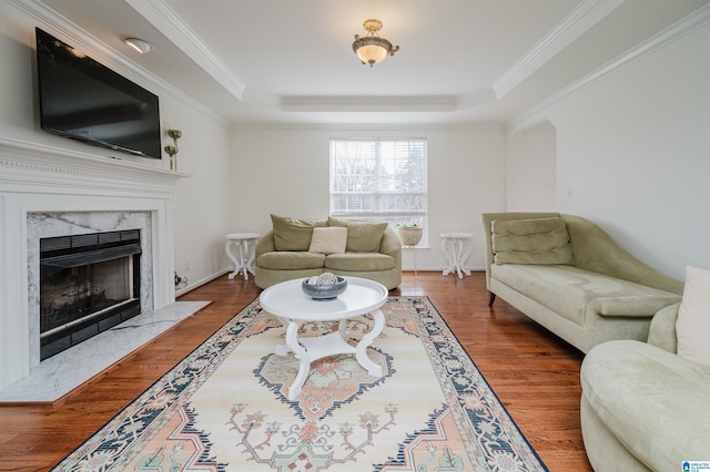 living room featuring a tray ceiling, a fireplace, ornamental molding, and dark hardwood / wood-style floors