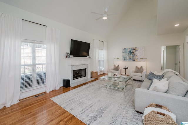 living room featuring hardwood / wood-style flooring, a fireplace, high vaulted ceiling, and ceiling fan