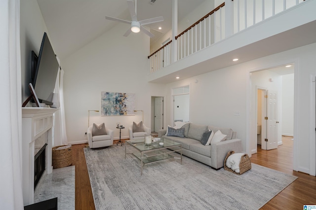 living room featuring ceiling fan, wood-type flooring, and a towering ceiling