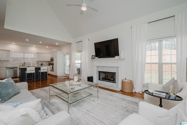 living room featuring a fireplace, high vaulted ceiling, dark hardwood / wood-style floors, and ceiling fan