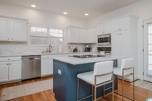 kitchen with stainless steel appliances, white cabinetry, and a kitchen island