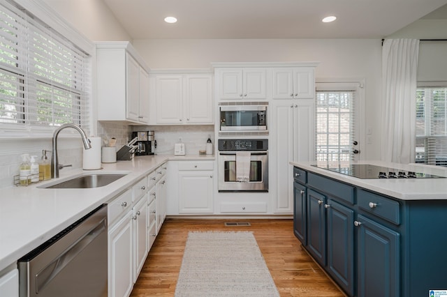 kitchen featuring appliances with stainless steel finishes, blue cabinetry, sink, and white cabinets