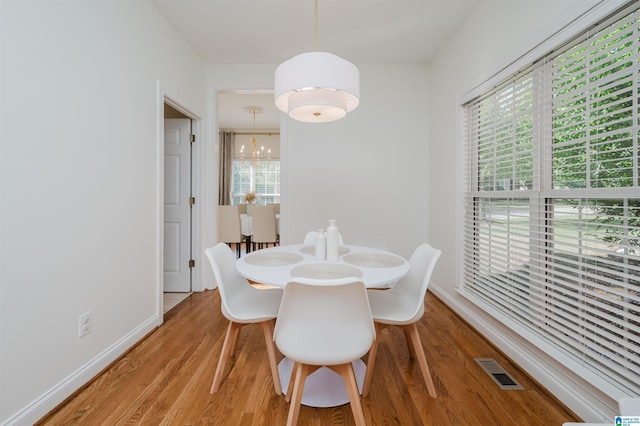 dining space featuring hardwood / wood-style floors, a wealth of natural light, and a chandelier