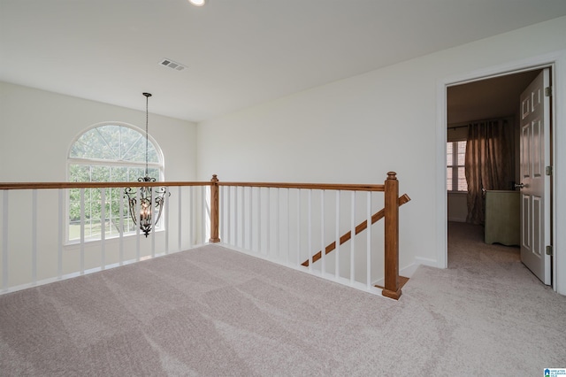 hall with carpet and an inviting chandelier