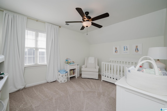 bedroom with light carpet, vaulted ceiling, a nursery area, and ceiling fan