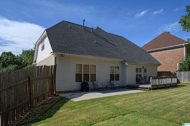 rear view of house with a wooden deck, a patio area, and a lawn